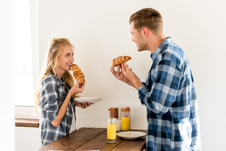 side view of young couple having breakfast in kitchen at homeの写真素材