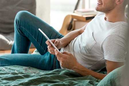 cropped shot of man with tablet lying on bed at homeの写真素材