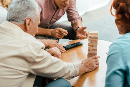 cropped shot of mature friends playing with wooden blocks on table at homeの写真素材