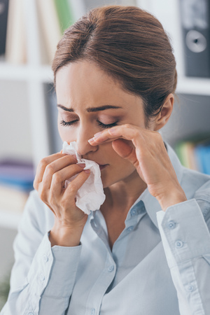 close-up portrait of crying adult businesswoman with paper napkin at officeの写真素材