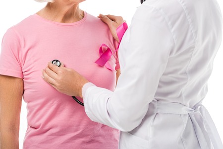 cropped shot of doctor with stethoscope checking health of senior woman with breast cancer awareness ribbon isolated on whiteの写真素材
