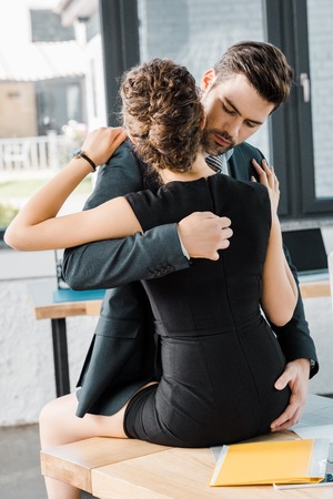 passionate businessman unzipping dress of seductive businesswoman at workplace in officeの写真素材