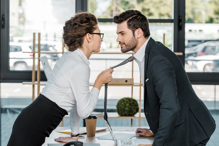 side view of businessman and businesswoman flirting at workplace in officeの写真素材