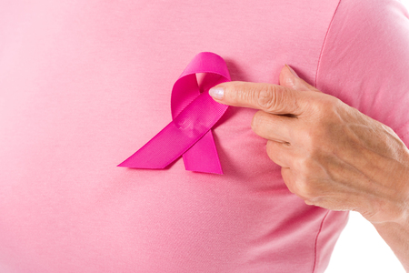 cropped shot of woman in pink t-shirt pointing with finger at breast cancer ribbonの写真素材