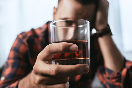close-up shot of depressed man holding glass of whiskeyの写真素材