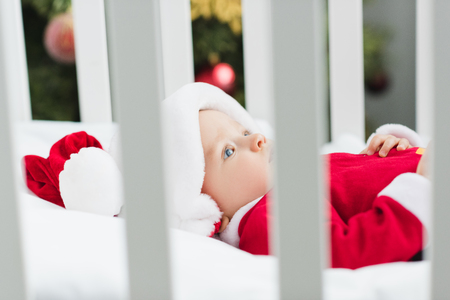 close-up shot of adorable little baby in santa suit lying in cribの写真素材