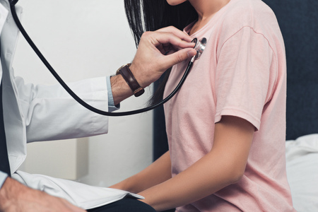 cropped shot of doctor listening breath of female patientの写真素材