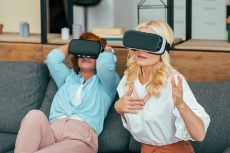 beautiful mature women sitting on couch and using virtual reality headsetsの写真素材