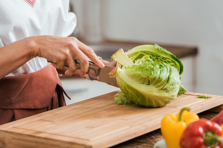 cropped image of woman preparing salad for dinner and cutting cabbage at homeの写真素材