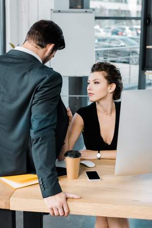 young seductive businesswoman flirting with colleague at workplace in officeの写真素材
