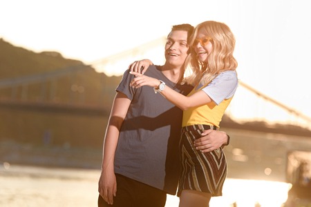 girlfriend pointing on something to boyfriend on river beach in evening