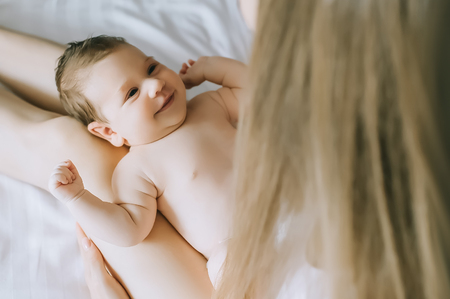 partial view of mother playing with adorable baby boy in bed at homeの写真素材