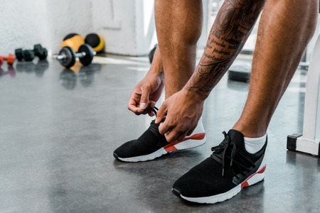 partial view of young sportsman tying shoelaces in gymの写真素材
