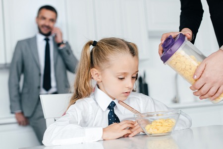 selective focus of kid in school uniform at table with breakfast and parents at home, back to school conceptの写真素材