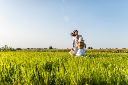 beautiful smiling mother and daughter playing in green meadowの写真素材