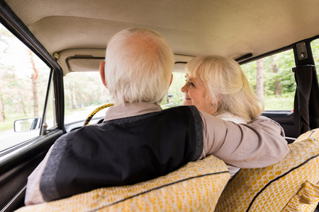 back view of senior husband and wife in beige carの写真素材