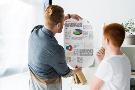 father showing diagram to pensive son at homeの写真素材
