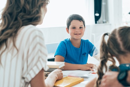 partial view of mother and kids doing homework together at home