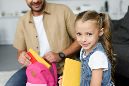 partial view of daughter and father packing backpack for first day at school, back to school conceptの写真素材