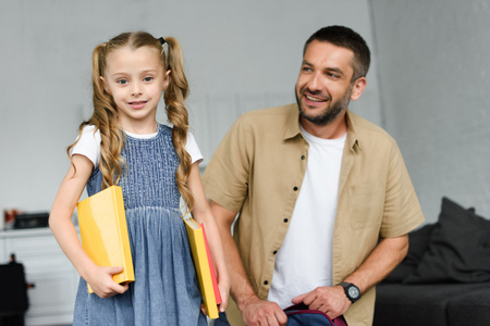 portrait of little kid with books and father behind at home, back to school conceptの写真素材