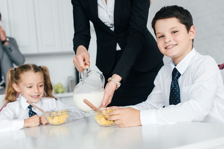 partial view of kids in school uniform and parents during breakfast at home, back to school conceptの写真素材