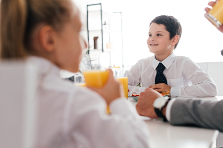 partial view of father and kids in school uniform having breakfast at homeの写真素材
