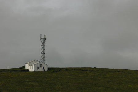 landscape with two houses near electric tower under cloudy sky in Vik, Icelandの写真素材