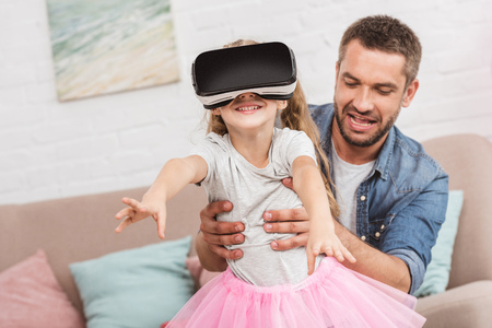 father and daughter having fun and using virtual reality headset on sofaの写真素材