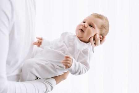 cropped image of father carrying little baby boy in front of curtains at homeの写真素材
