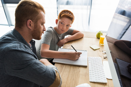 side view of father helping son doing homework at homeの写真素材