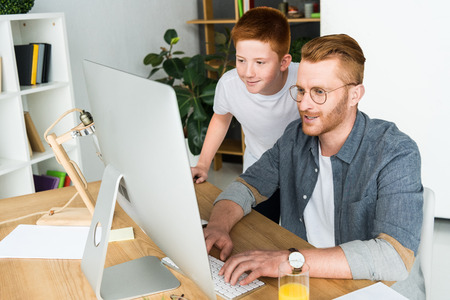 father and son looking at computer at homeの写真素材