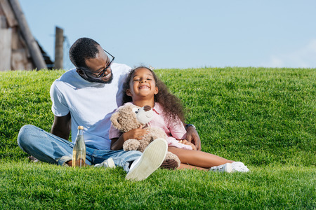 Happy African american father and daughter in amusement parkの写真素材