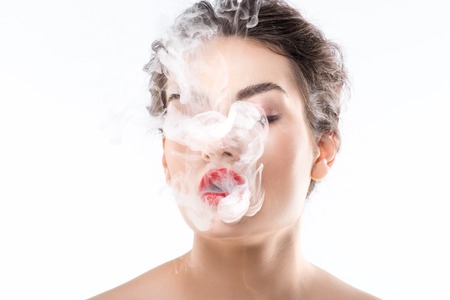 Beautiful woman blowing smoke, isolated on whiteの写真素材
