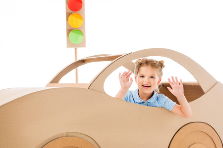 Adorable kid playing with cardboard car and traffic lights, isolated on whiteの写真素材