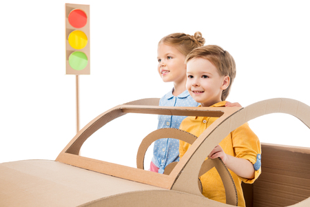 Adorable siblings playing with cardboard car and traffic lights, isolated on whiteの写真素材