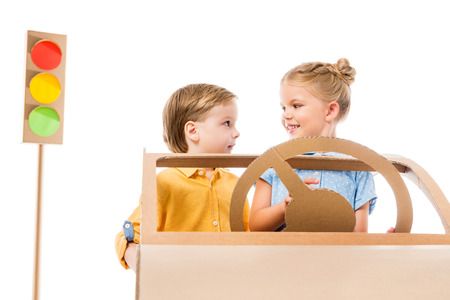 Adorable children driving cardboard car with traffic lights on background, isolated on whiteの写真素材