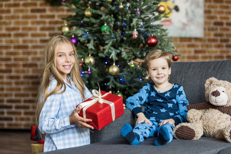 adorable happy children with christmas present smiling at camera
