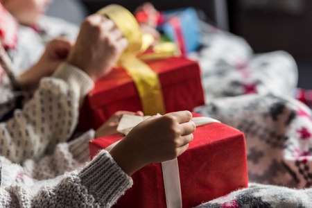 cropped shot of young couple in winter sweaters opening christmas presentsの写真素材