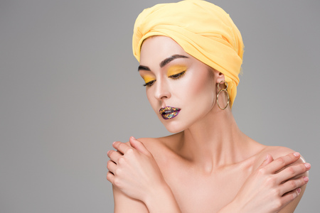 beautiful sensual naked girl in yellow head wrap looking down isolated on greyの写真素材