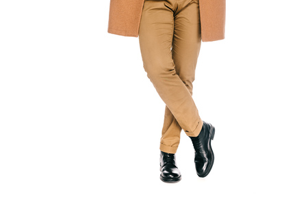 cropped shot of man in stylish pants, leather shoes and brown overcoat standing isolated on whiteの写真素材