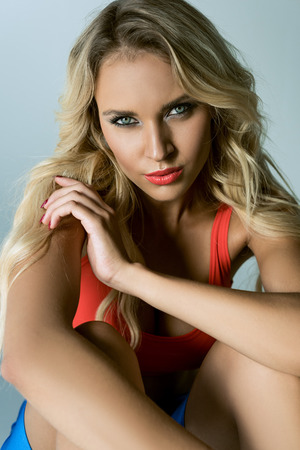 attractive sporty young woman looking at camera on greyの写真素材