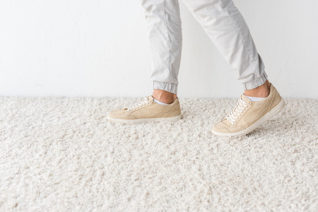 cropped view of male legs on carpet against white wallの写真素材