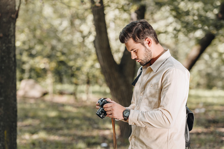 side view of tourist with photo camera in hands in autumn parkの写真素材