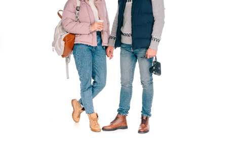 low section of young tourists holding camera and coffee to go isolated on white