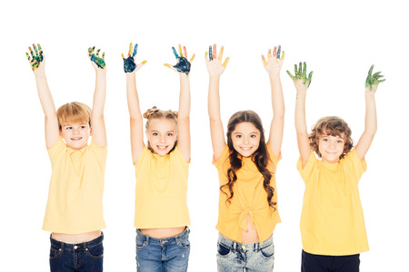 adorable happy kids showing hands in paint and smiling at camera isolated on whiteの写真素材