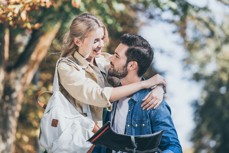 portrait of young travelers with map hugging in autumn parkの写真素材