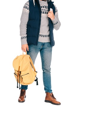 cropped shot of stylish young traveler holding backpack and smartphone isolated on whiteの写真素材