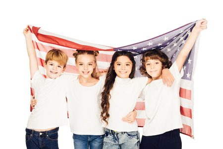 smiling adorable children standing under american flag and looking at camera isolated on whiteの写真素材