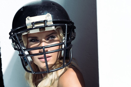 close-up portrait of young woman in sport bra and american football helmet on whiteの写真素材