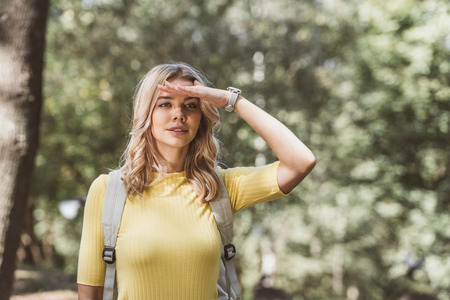 portrait of beautiful young woman with backpack looking away in parkの写真素材
